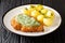 Portion of fried breaded schnitzel with boiled potatoes and Frankfurt green sauce close-up in a plate. horizontal