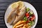 Portion of fried Salema porgy fish with lemon, french fries and fresh vegetable salad close-up on a plate. horizontal top view