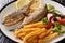 Portion of fried Salema porgy fish with lemon and fresh vegetable salad close-up on a plate. horizontal