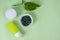 Portion green capsules for skin health, two face cream tube near plant leaf on green background. Woman's care, detox