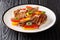 Portion of grilled pork chop with bell peppers, onions and basil close-up in a plate. horizontal