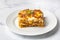 Portion of ground beef lasagna topped with melted cheese and garnished with fresh parsley served on a plate in close view for a