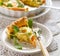 Portion of quiche with  boiled egg and leek sprinkled with fresh lambs lettuce and dill on a white plate