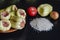 Portion of raw stuffed bell peppers on brown clay plate and raw ingredients nearby