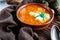 A portion of red borscht in a brown plate, next to an old wooden Board garlic and quail egg, green leeks and driftwood. White sour