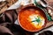 A portion of red borscht in a brown plate, next to an old wooden Board garlic and quail egg, green leeks and driftwood. White sour