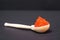 Portion of red salmon caviar lies in handmade wooden spoon, black background, front view, close up. Tasty luxury