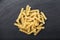 A portion of Rotini corkscrew pasta on black stone table, top v