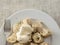 Portion of Russian dumplings with sour cream and chopped herbs on a white plate and metal fork