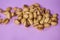 Portion of salted open pistachios on a lilac background