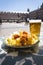 A portion of tapas in the Plaza Mayor in Madrid. Potatoes with alioli sauce and brava sauce with a beer.