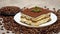 Portion of Traditional Italian Tiramisu dessert and coffee beans