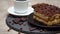 Portion of Traditional Italian Tiramisu dessert, cup of espresso and pieces of chocolate