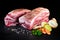 Portioned fresh raw pork shoulder with vegetables and spices prepared for cooking on dark background