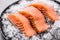 Portioned raw salmon fillets in ice on plate - Close-up