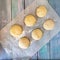 Portions of yeast dough for baking on parchment paper on a wooden table