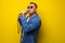 Portrai of mature middle age man in suit singing over the microphone isolated on yellow background. Singer concept.