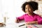 Portraif Of Smiling Black Preschooler Girl Drawing At Table In Kitchen