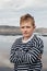 Portrait of 10 years caucasian boy with blonde hair standing in front of the lake in sunny day. Holiday domestic tourism