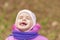 Portrait of 2-3 years old girl in pink warm autumn clothes and violet scarf crying with closed eyes. Expression of fear and pain