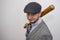 Portrait of a 35-year-old man in a cap and with a baseball bat on a light background of a threatening appearance. Concept: yard bu