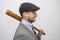 Portrait of a 35-year-old man in a cap and with a baseball bat on a light background of a threatening appearance. Concept: yard bu