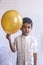 Portrait of 5-6 years old boy with balloon. Adorable middle eastern kid holding a golden balloon. Celebrating, holiday concept