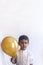 Portrait of 5-6 years old boy with balloon. Adorable middle eastern kid holding a golden balloon. Celebrating, holiday concept