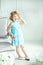 Portrait of 5 years old curly blonde smiling girl in blue dress and wreath. Little girl stay in studio with natural light in