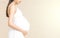 Portrait of 9 month pregnant young asian woman in white dress