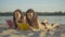 Portrait of absorbed young Caucasian women reading on sandy beach at summer resort. Beautiful brunette tourists lying on