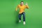 Portrait of active cheerful guy jump run wave hand greeting friend on green background