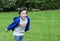 Portrait active little boy playing with toy airplane against green nature background, Child throwing foam airplane, Kid playing in