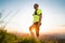 Portrait of Active mountain trail runner dressed bright t-shirt with backpack and sport sunglasses resting while he sky running by