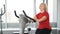 Portrait of active old woman in fitness club engaged in cardio training on a exercise bike. Healthy and active old woman