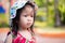 Portrait adorable Asian girl shows a suspicious expression. Little kid ware a red dress and a white hat with multicolor polka dots