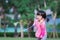Portrait of adorable Asian little girl holding badminton and knock shuttlecock racket on nature green lawn outdoor.