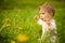 Portrait of adorable baby playing outdoor in the sunny dandelions field