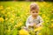 Portrait of adorable baby playing outdoor in the sunny dandelions field