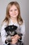 Portrait of adorable blond young girl smiling holding Schnauzer puppy