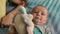 Portrait of adorable blue-eyed baby on the bed plays with toy