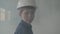 Portrait adorable boy in a protective helmet turning and looking at the camera in the background of smoke indoors