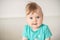 Portrait of adorable Caucasian baby girl with blue eyes, looking at the camera calmly, with curiosity