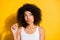 Portrait of adorable dark skin lady arm fingers play with hair curls look empty space isolated on yellow color