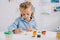 portrait of adorable focused child drawing picture with paints and brush