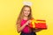 Portrait of adorable glad child girl with long blond hair and angelic halo holding gift box and smiling to camera