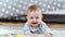 Portrait of adorable little cute baby smiling lying on fluffy carpet at home looking at camera