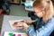 Portrait of adorable little girl smiling happily while enjoying art and craft lesson in art school working together with other