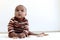 Portrait of adorable six month crawling African American baby playing with wooden developmental toys on fluffy white rug, happy