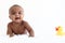 Portrait of adorable six month crawling African American baby playing with yellow duck toy on fluffy white rug, happy smiling